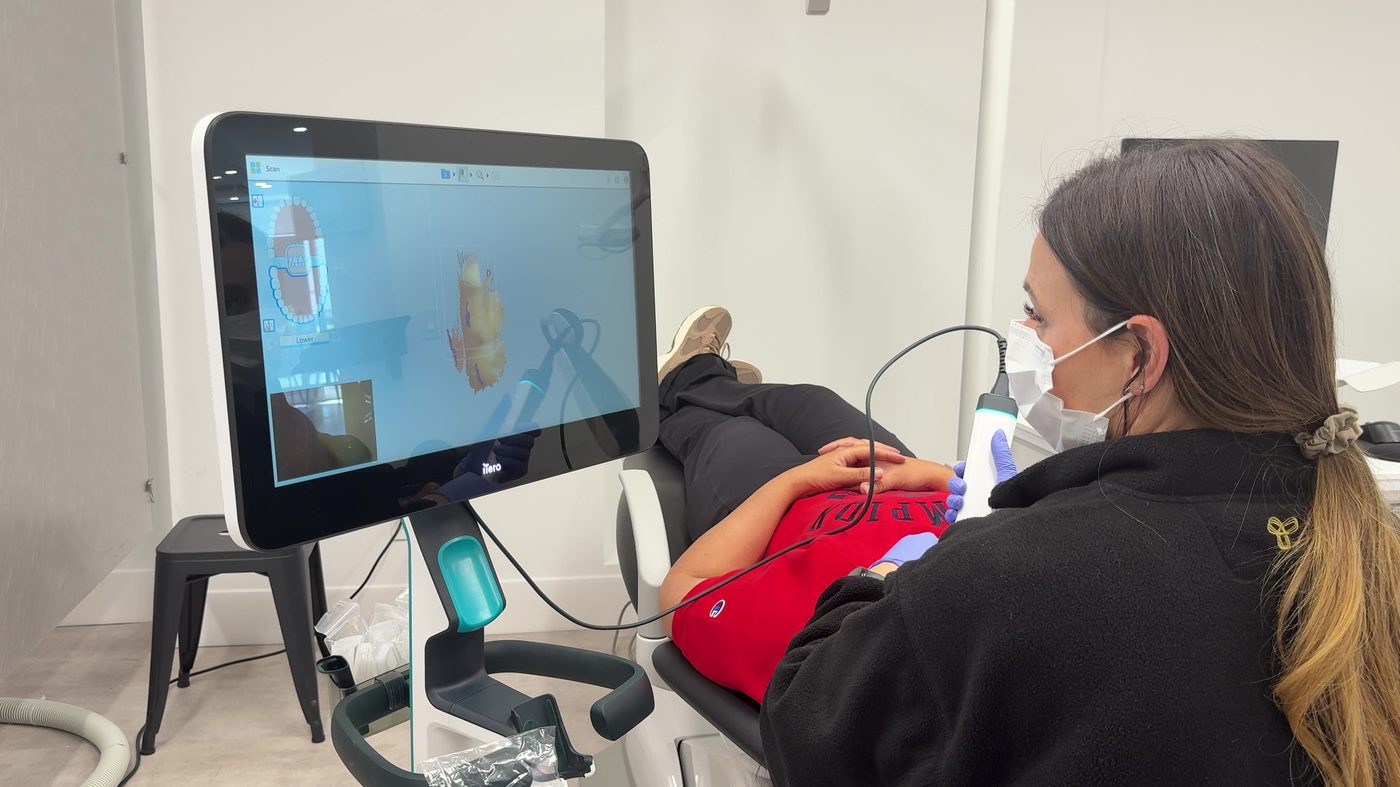A patient receiving a goop-free iTero digital scan with a live 3D model on screen